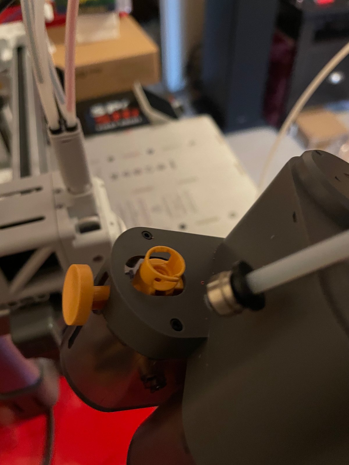 Close-up of the AMS Lite feeder with the yellow fitting exposed and the tube connector alongside it