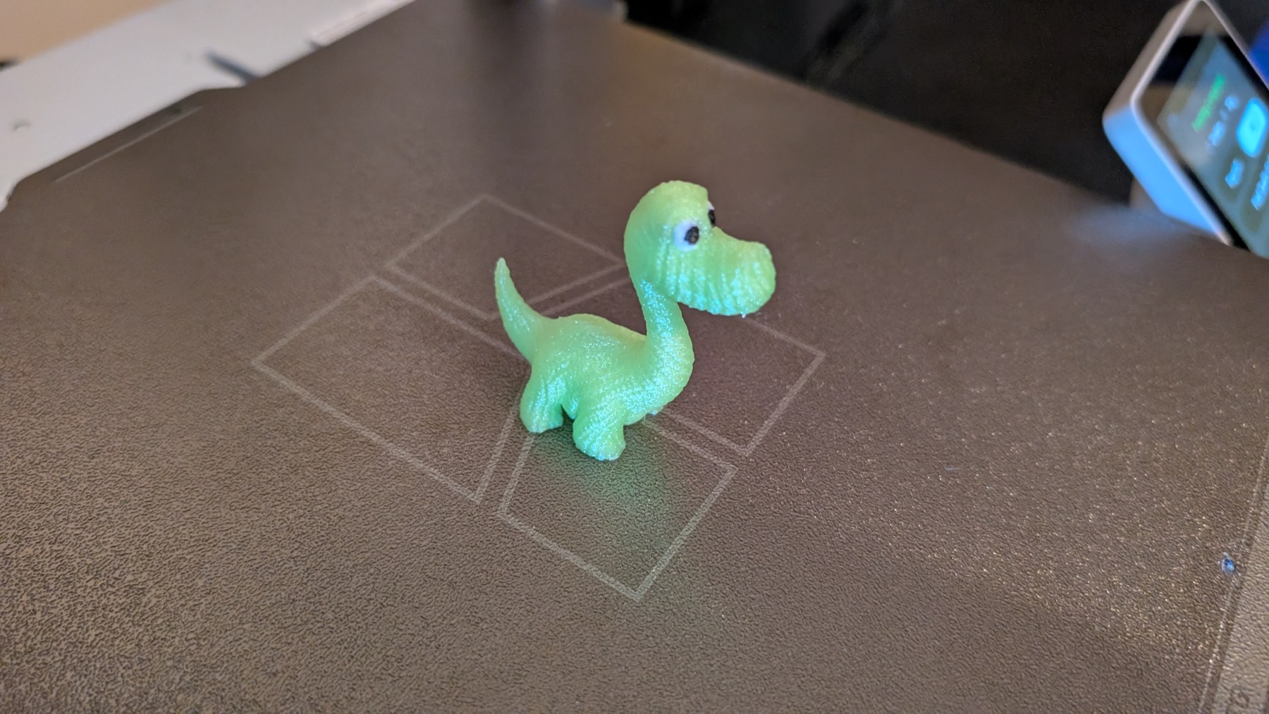 Finished green dinosaur standing on the printer build plate