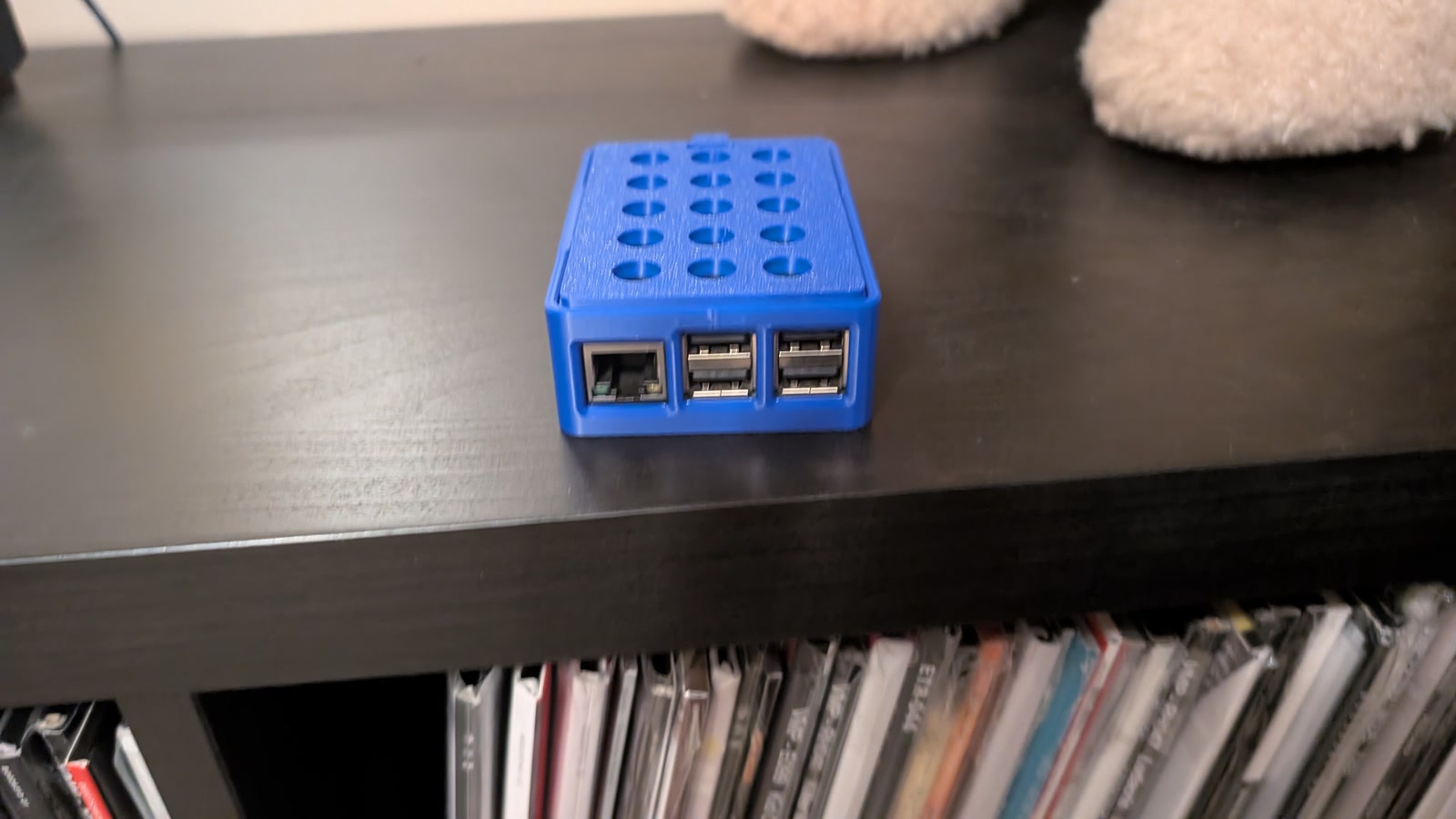 Blue vented Raspberry Pi and HiFiBerry enclosure on a shelf