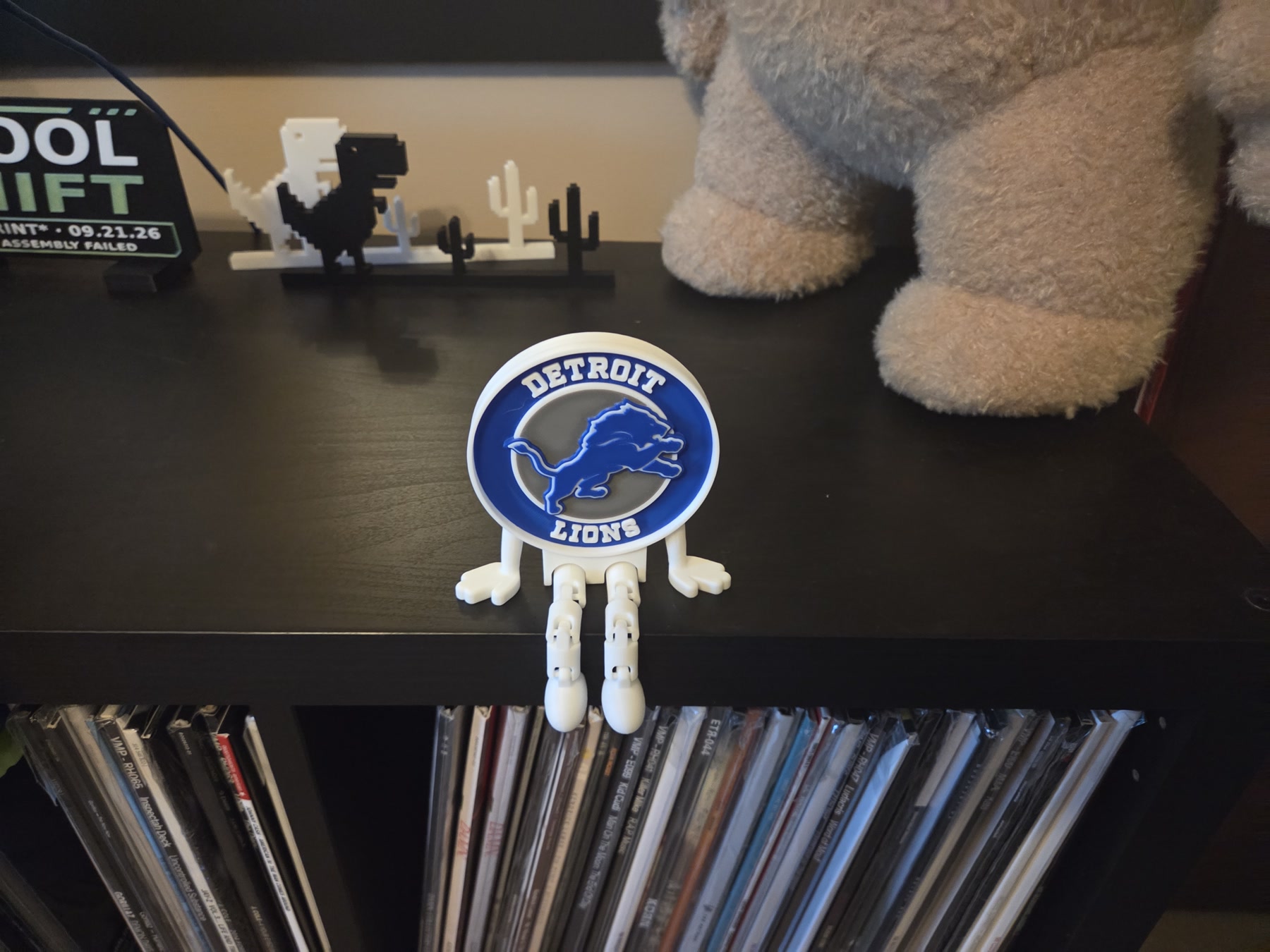Blue and white Detroit Lions Buddy sitting on a shelf with articulated legs