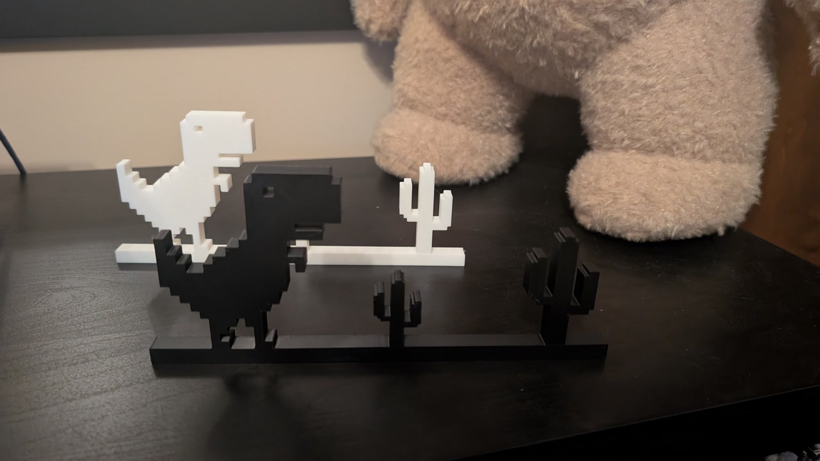 Black and white pixel dinosaurs and cacti on a shelf