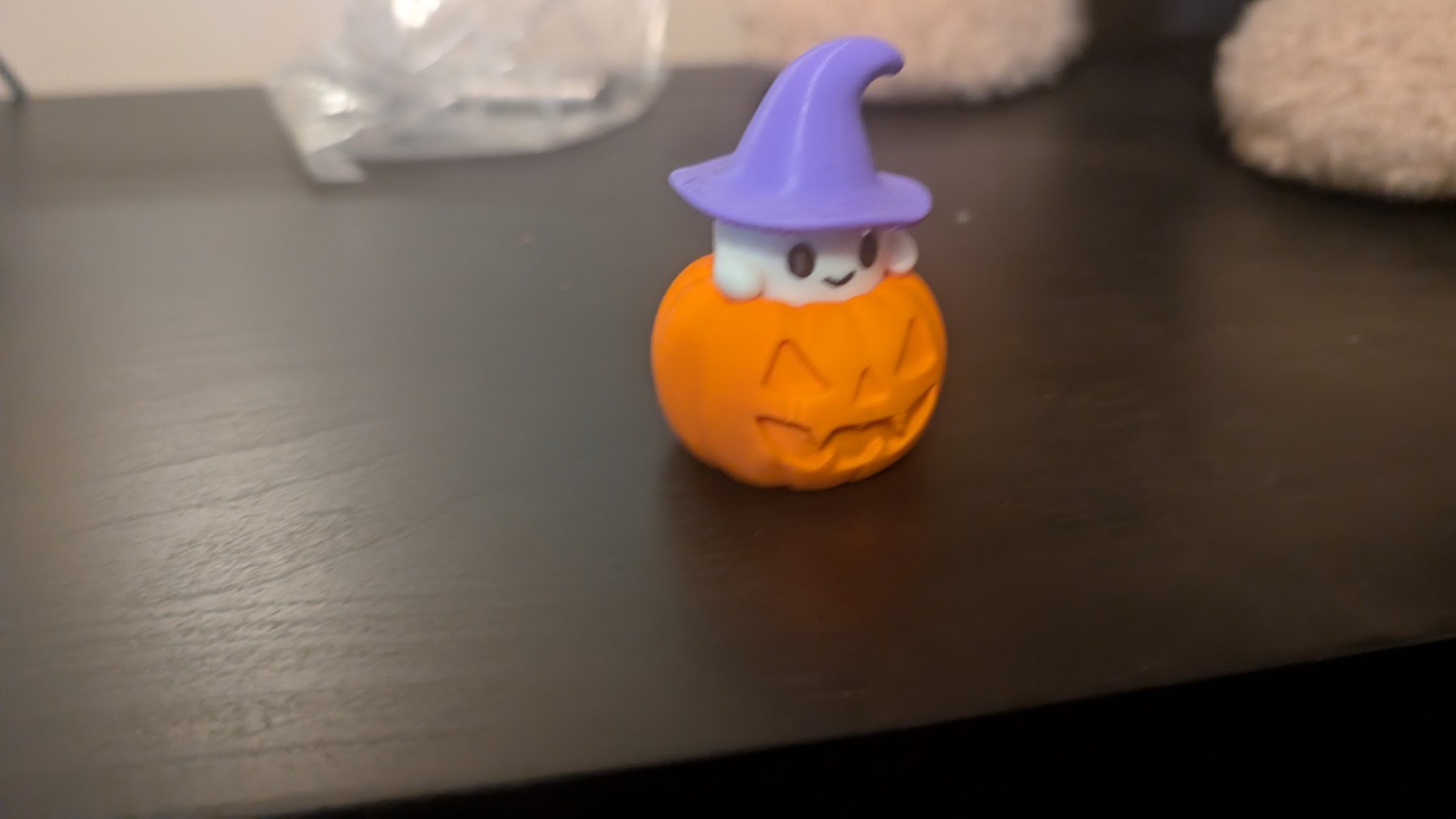 White ghost in an orange jack-o’-lantern wearing a purple witch hat