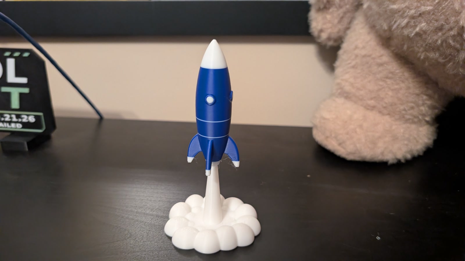 Blue and white rocket rising from a printed white smoke cloud