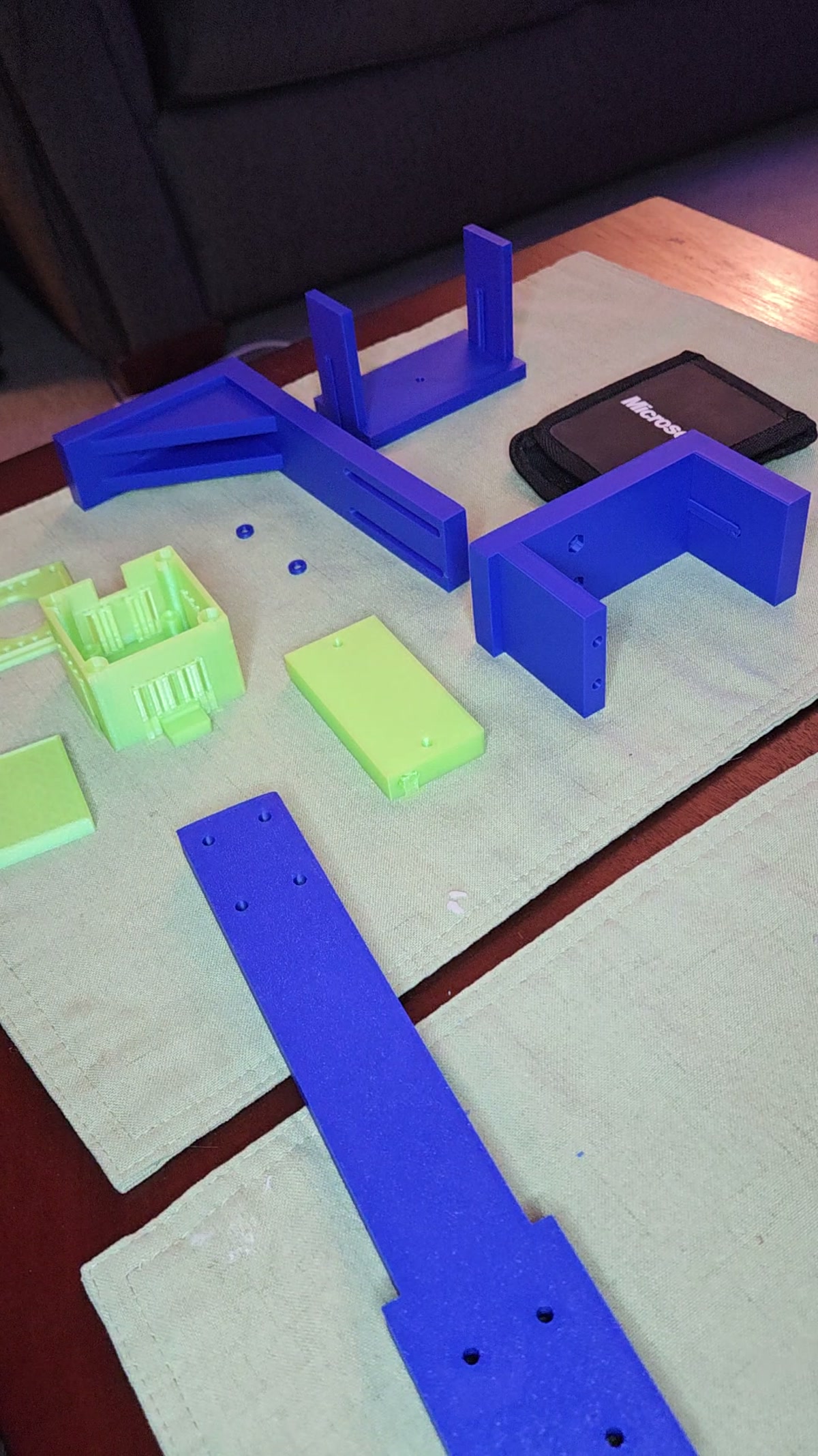 Blue shelf-mount parts and lime camera housing laid out for assembly