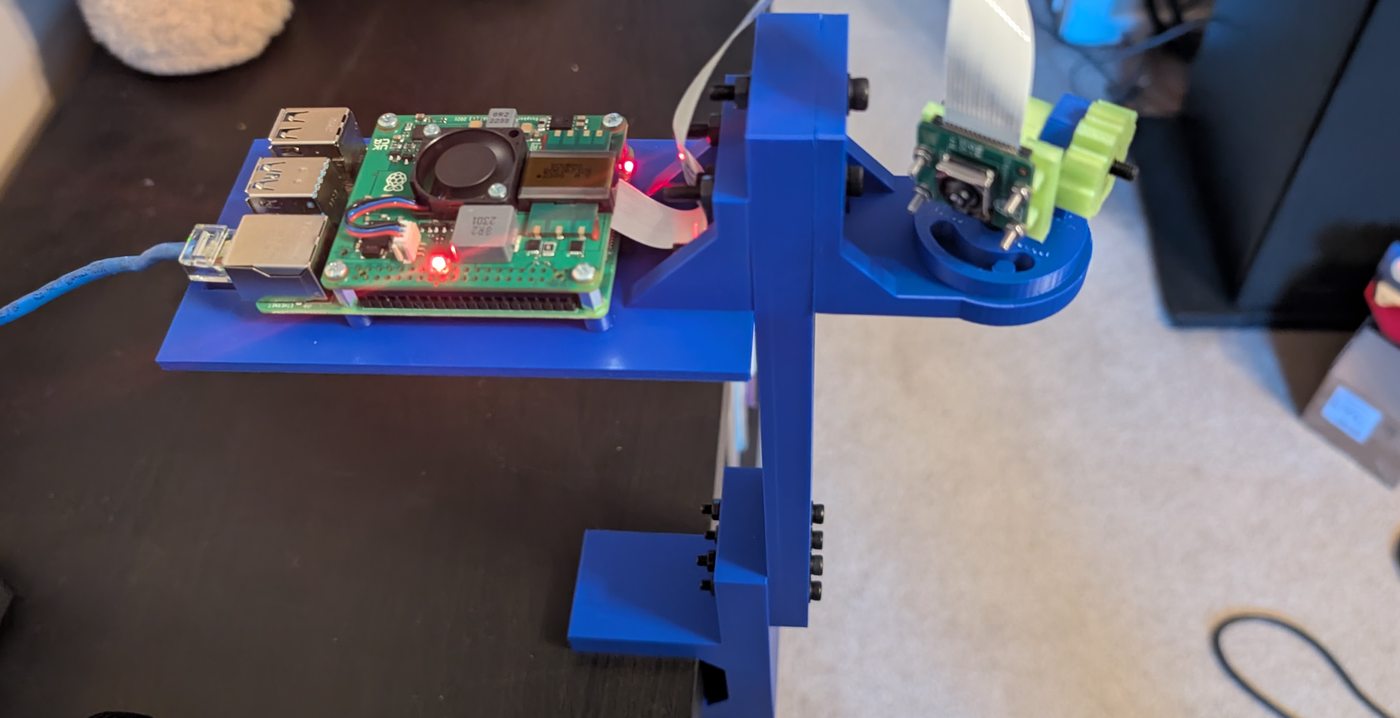 Raspberry Pi and ribbon-connected camera fitted to the blue printed tray and adjustable head