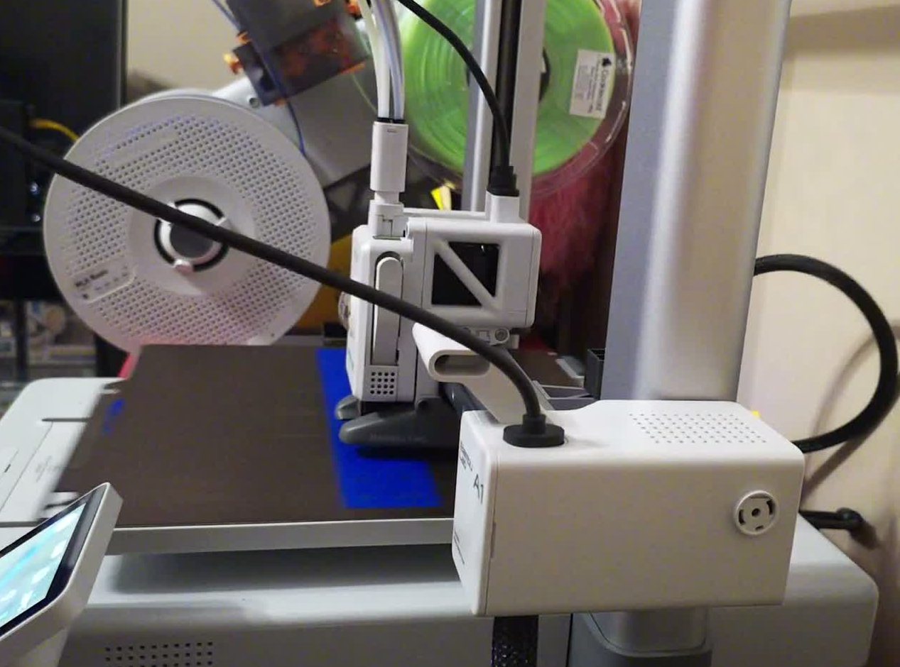 Bambu Lab A1 printing the blue upright for the camera mount