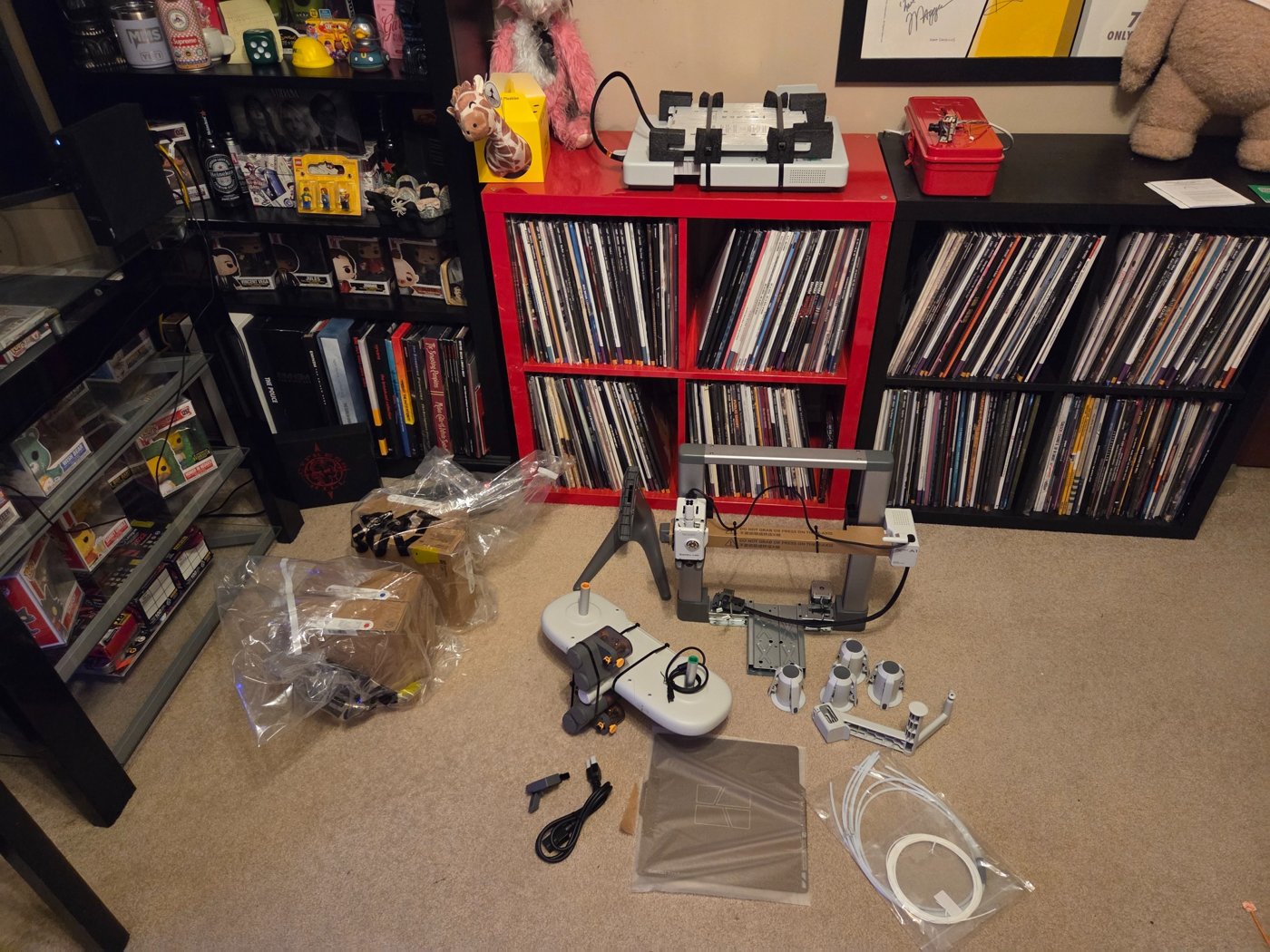 Bambu Lab A1 Combo frame, AMS Lite parts, cables, and accessories laid out with the printer base on the red cabinet